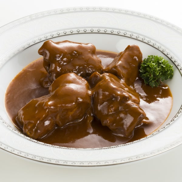 白い皿に盛られたたっぷり牛たんシチューと、添えられたパセリ