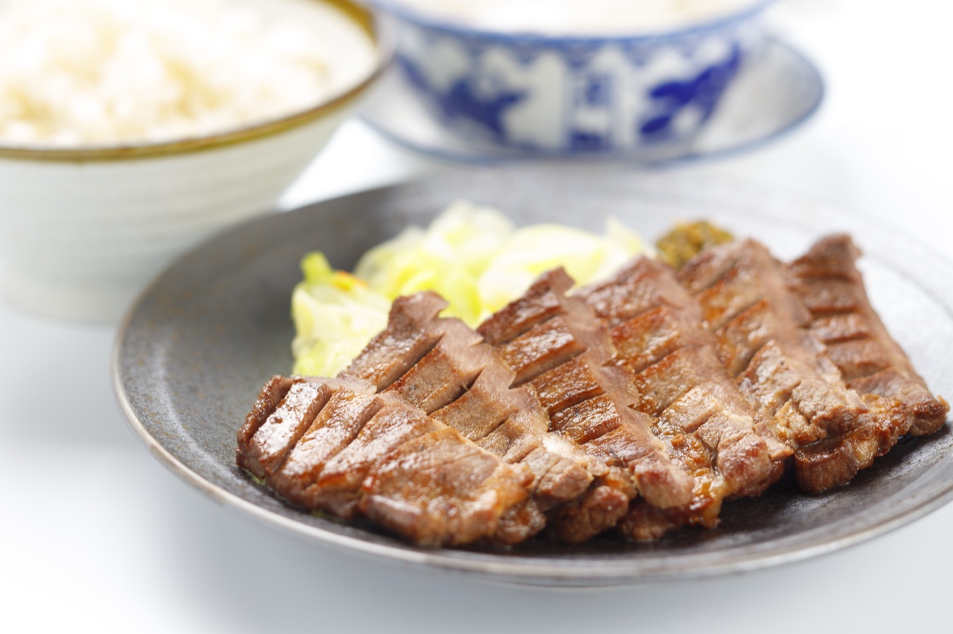 炭火で焼き上げた牛たん焼き。奥に麦飯とテールスープが並ぶ喜助の定食
