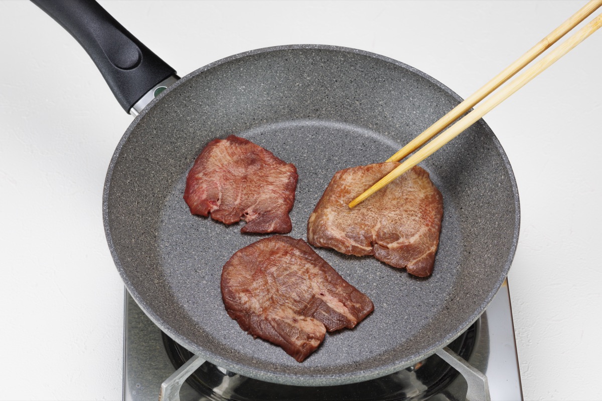 フライパンで牛たんを3枚焼き、箸で返しているところ