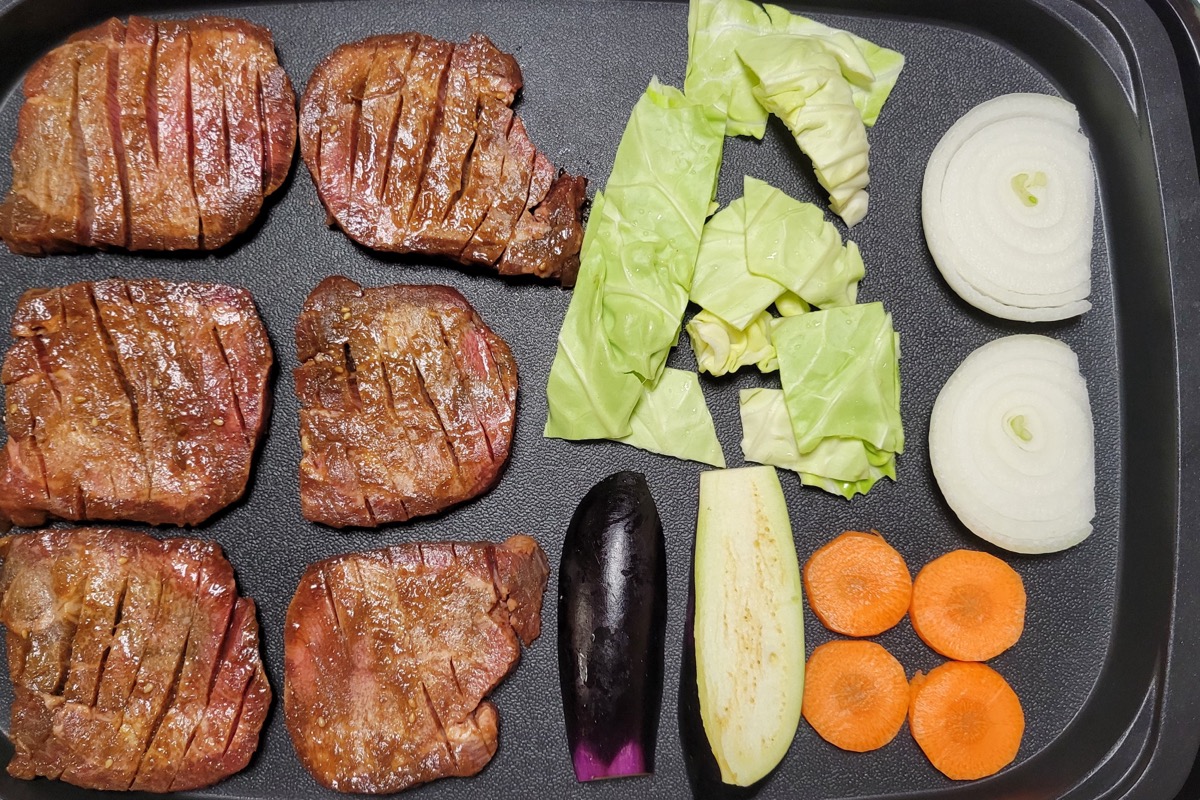 ホットプレートで切り込み入りの厚切り牛たんを、野菜と一緒に焼いているところ