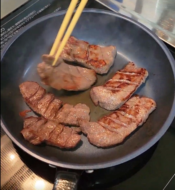 片面が焼き上がった牛たんを、箸で裏返しているところ